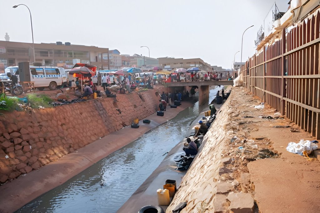 Nakivubo Channel in Kampala, Uganda showing drainage system challenges and community activity along the waterway.
