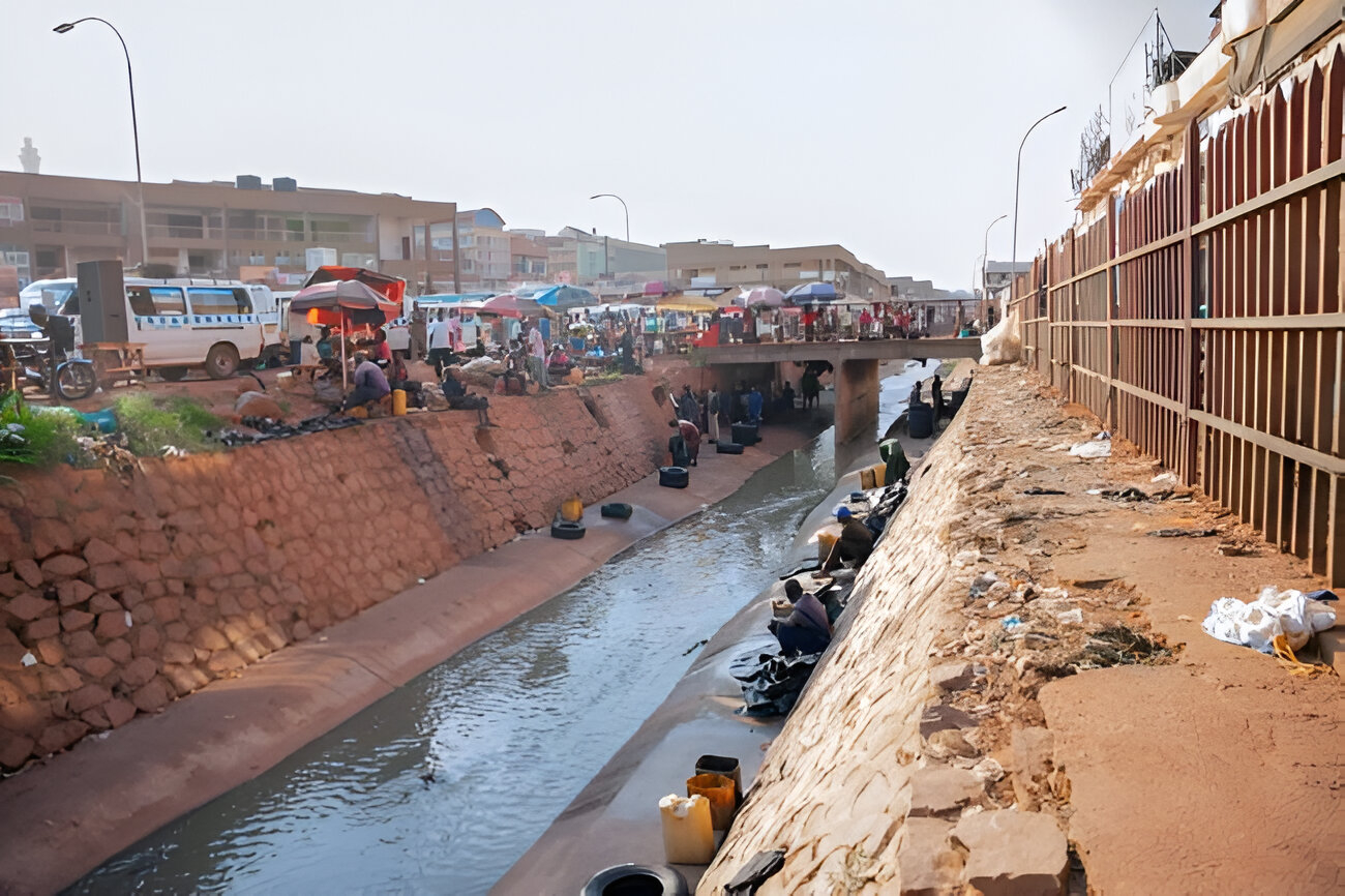 Nakivubo Channel in Kampala, Uganda showing drainage system challenges and community activity along the waterway.