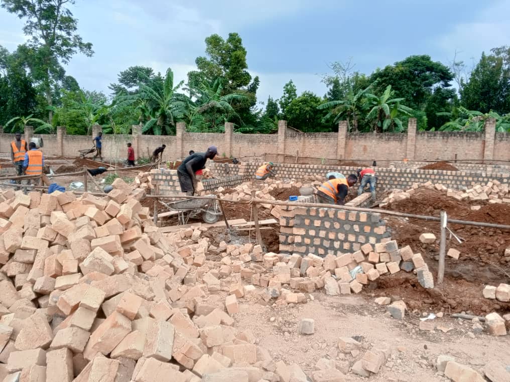 Young construction workers on site in Uganda working with modern tools.